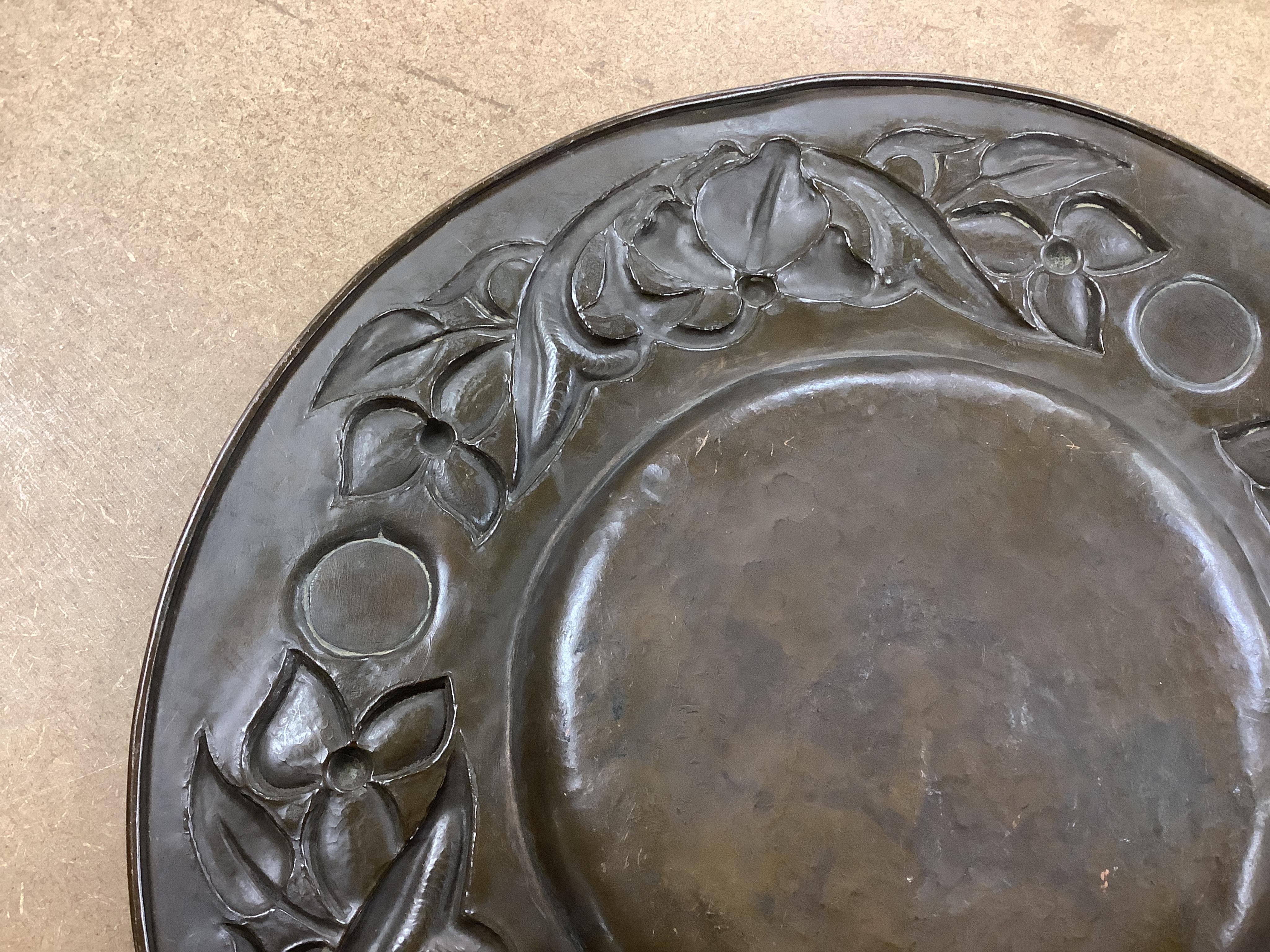 An Arts and Crafts embossed copper dish, in the manner of John Pearson, inlaid with Ruskin cabochons, unsigned, 32cm in diameter